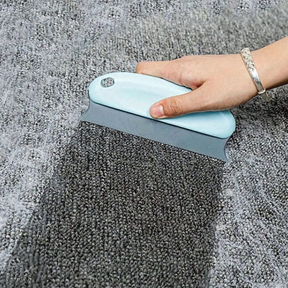 Light blue pet hair remover pulling a strip of hair off a grey carpet
