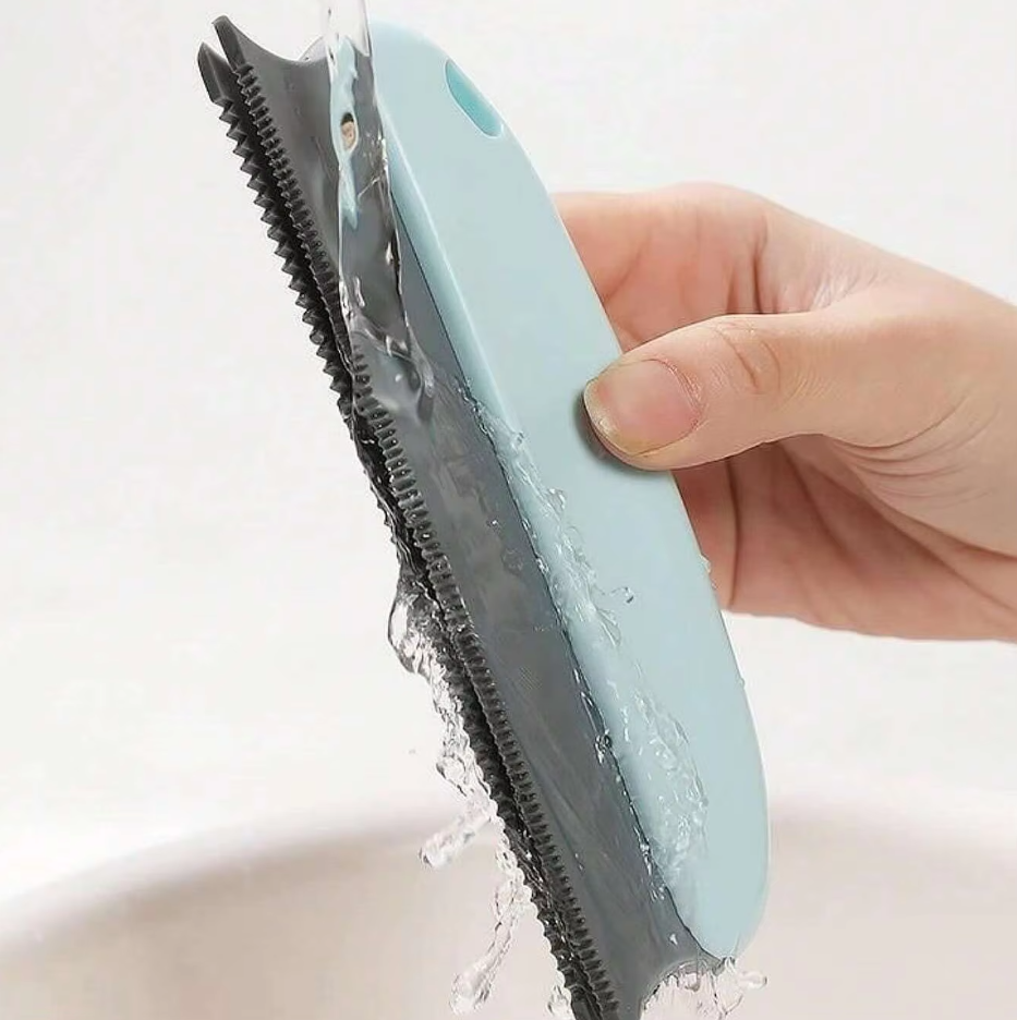 The light blue pet hair remover being rinsed under running water, its fine teeth showing