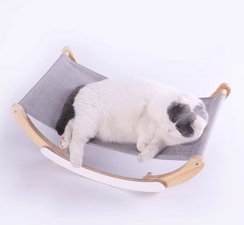 A large grey and white cat asleep in the grey sling of the wooden rocking cat hammock