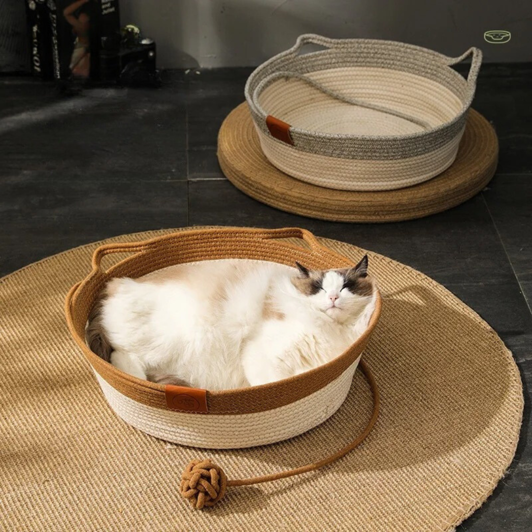 A cat curled up in the cotton rope basket bed on a round wooden table