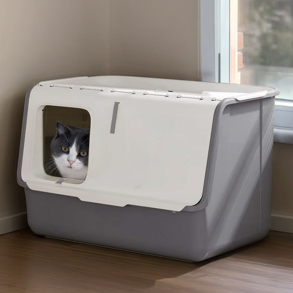 A grey and white cat looking out of the front flap door of the white and grey hooded litter box