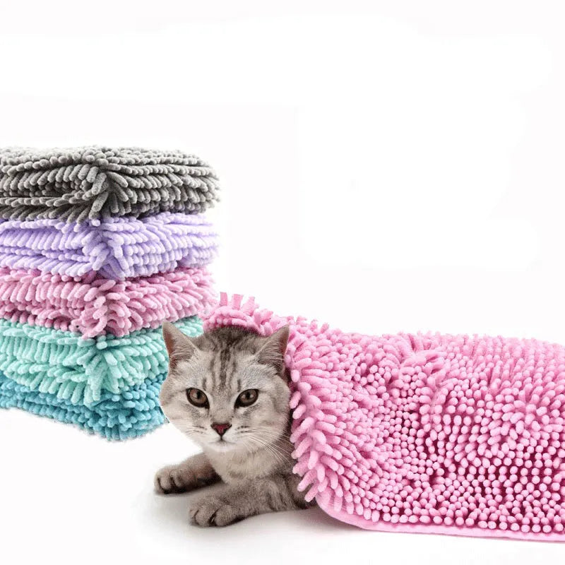 Grey, lilac, pink and turquoise chenille pet towels stacked beside a tabby cat under a pink towel