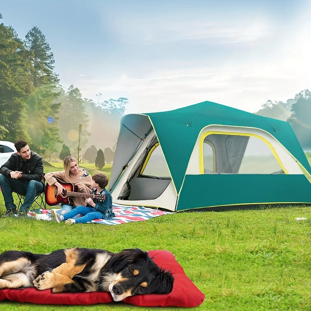 A dog lying on the red travel bed on the grass beside a tent