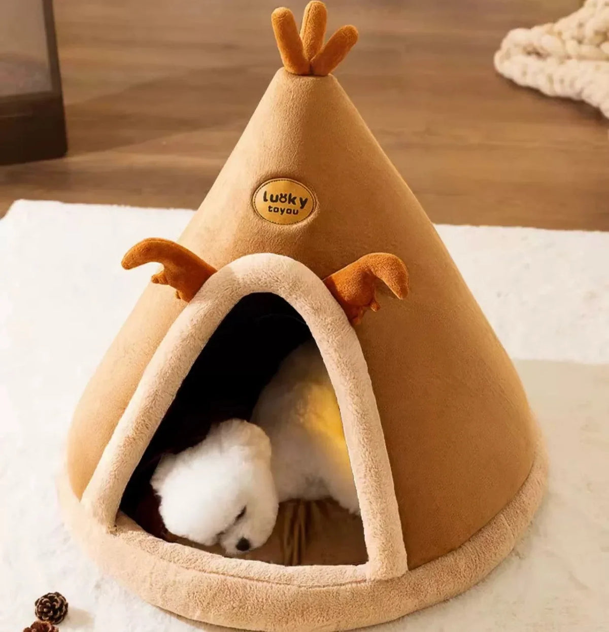 A small white dog asleep inside the caramel teepee cave bed