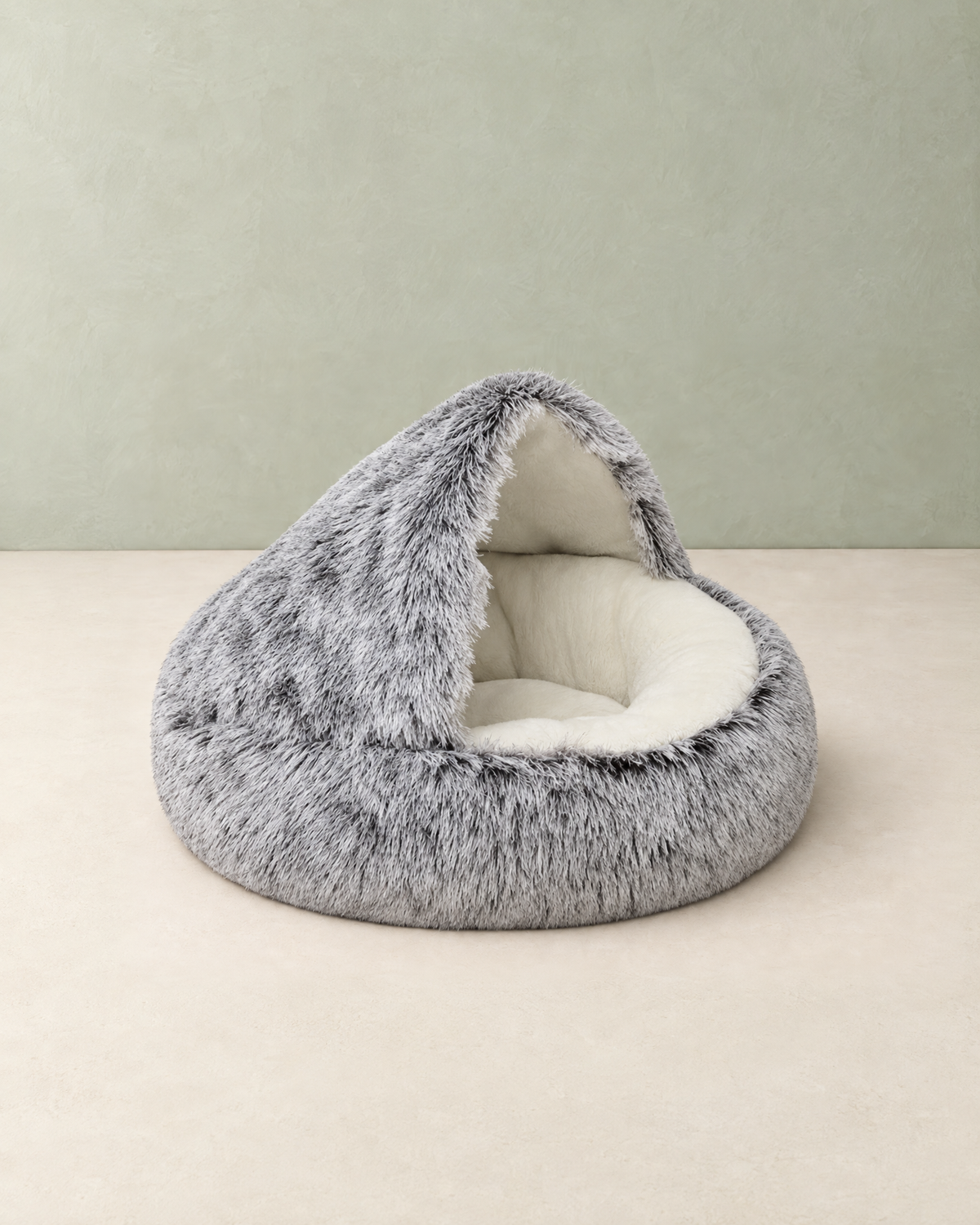 Grey frosted plush hooded cave bed with a cream fleece lining, standing on a cream floor against a pale sage wall
