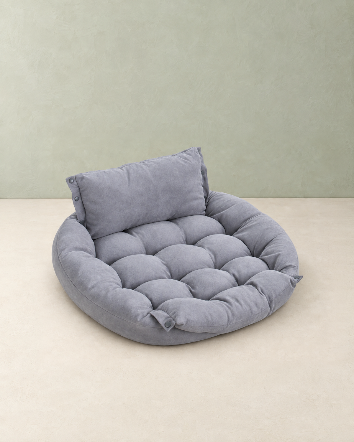 Grey tufted convertible dog bed folded into its bed shape with a pillow backrest, on a cream floor against a pale sage wall