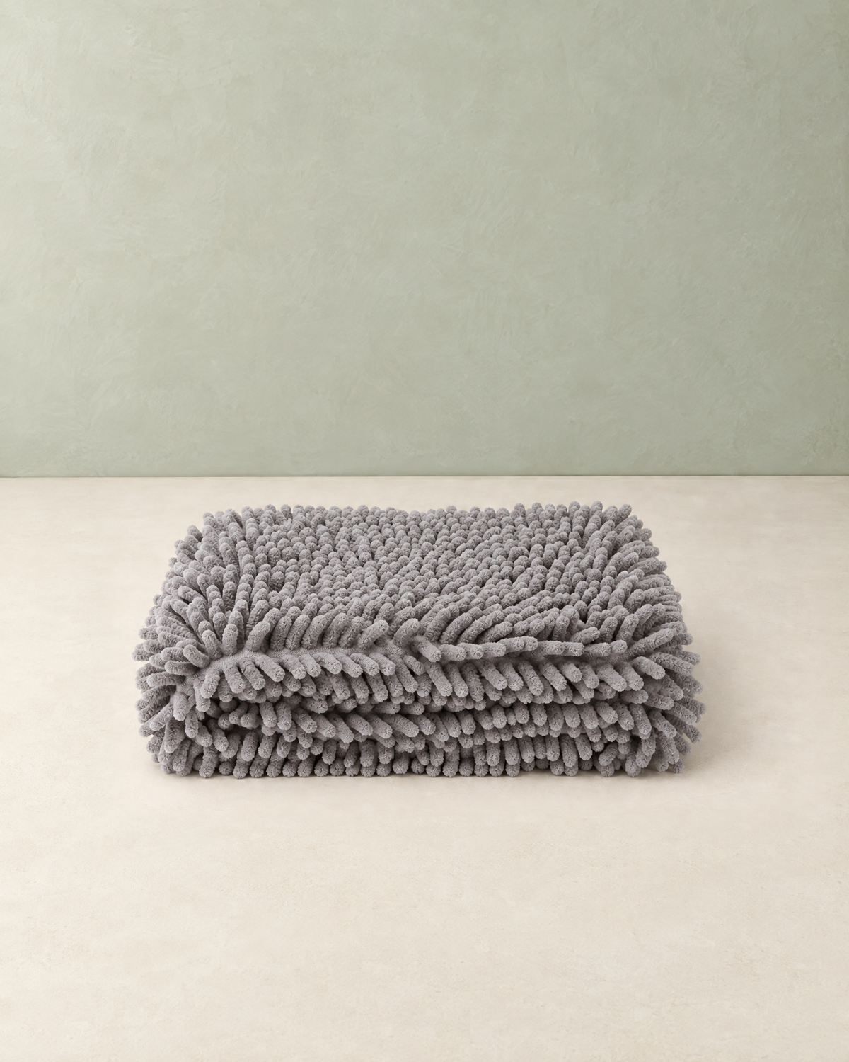 Grey chenille pet towel folded flat on a cream floor against a pale sage wall