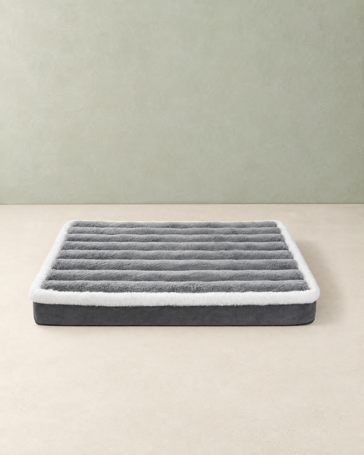 Grey foam dog bed mattress with a ribbed plush top and white fleece edge, on a cream floor