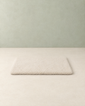 Cream fleece self-warming pet mat lying flat on a cream floor against a pale sage wall