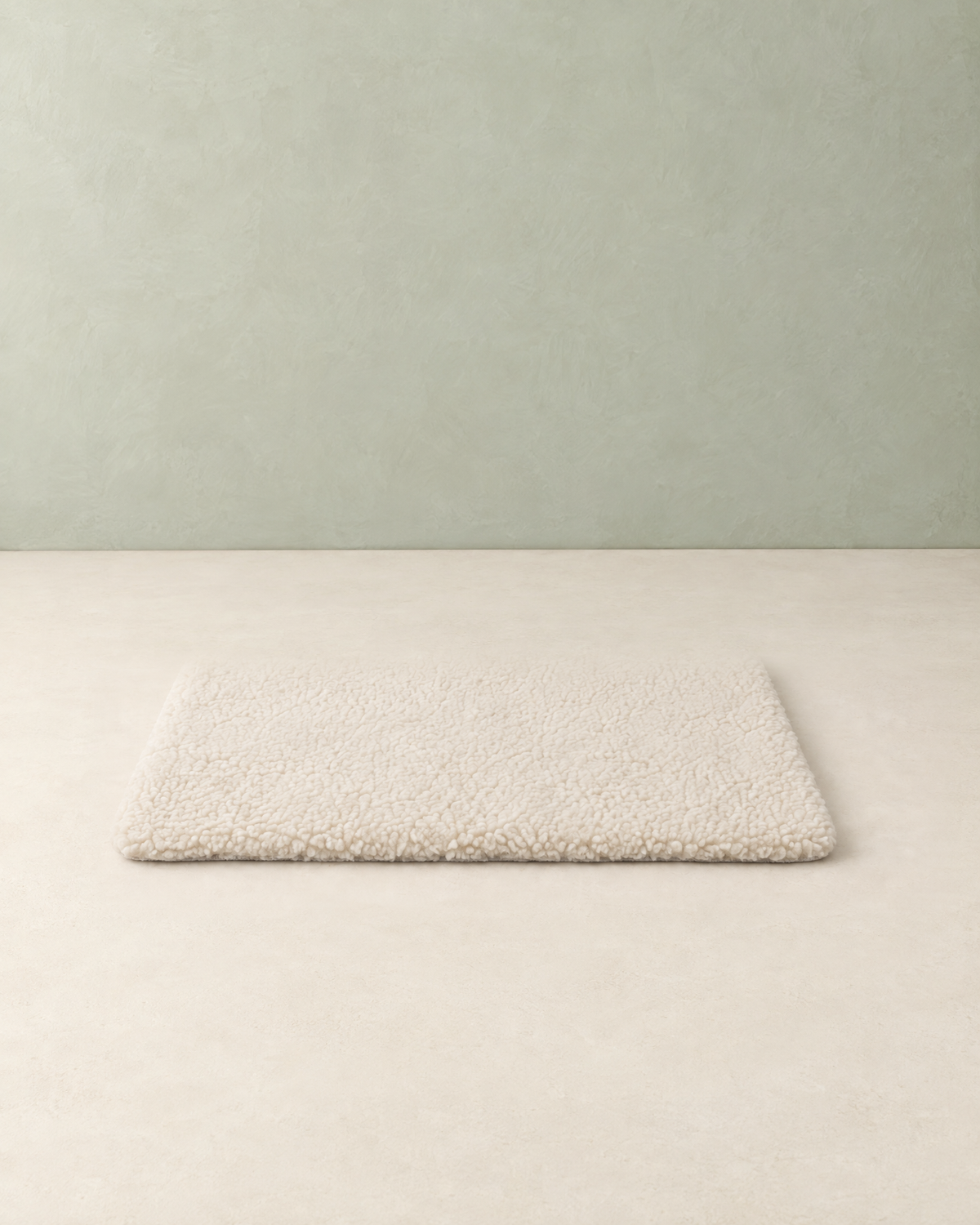 Cream fleece self-warming pet mat lying flat on a cream floor against a pale sage wall