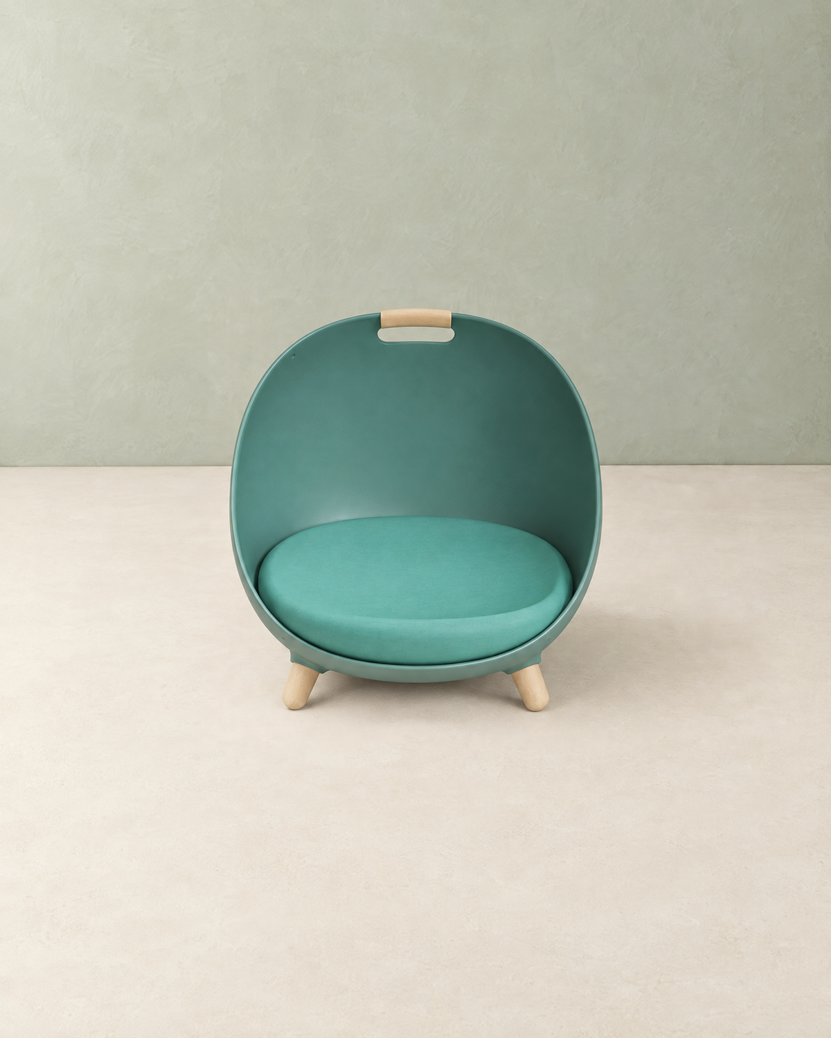 Teal green egg-shaped cat bed with a round cushion, wooden legs and a wooden carry grip, on a cream floor