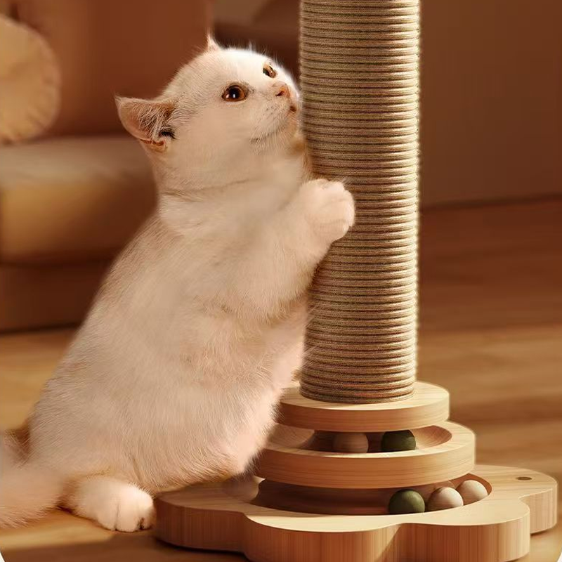 A white kitten stretching up to scratch the sisal post above the ball track base