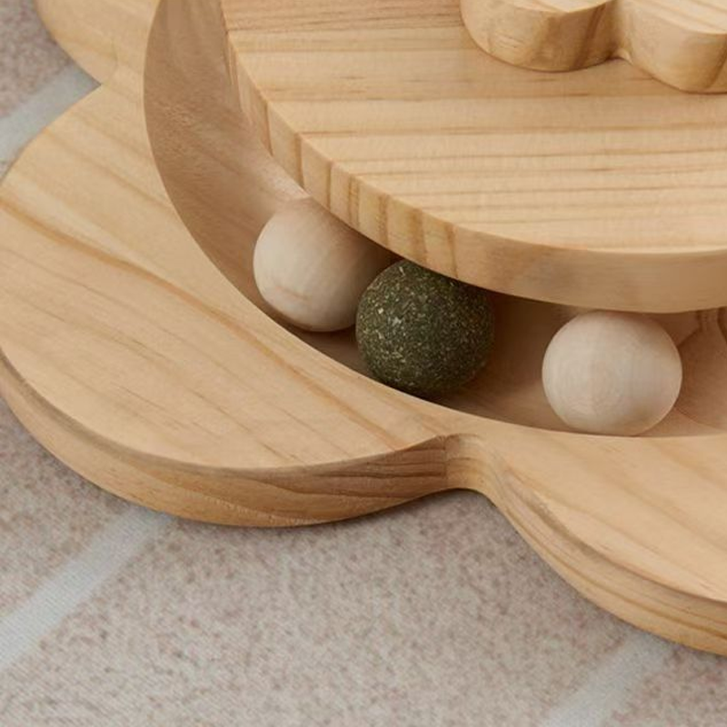 Close view of the ball track in the wooden base with two wooden balls and a green catnip ball