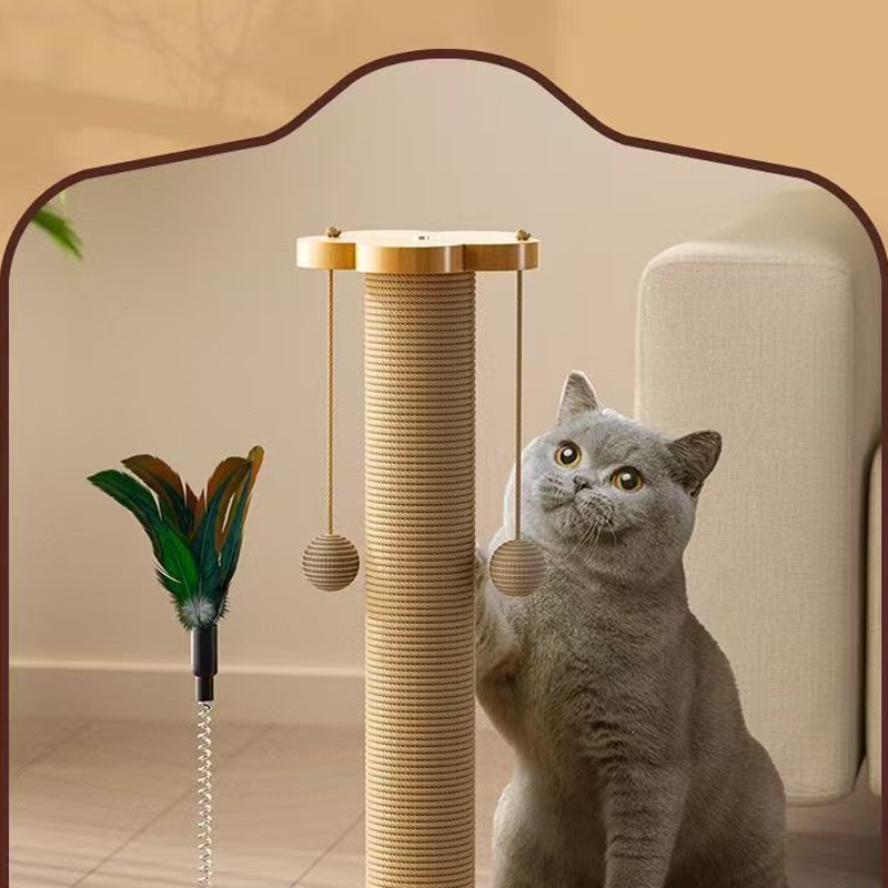 A grey cat standing beside the sisal scratching post with its feather wand and hanging balls