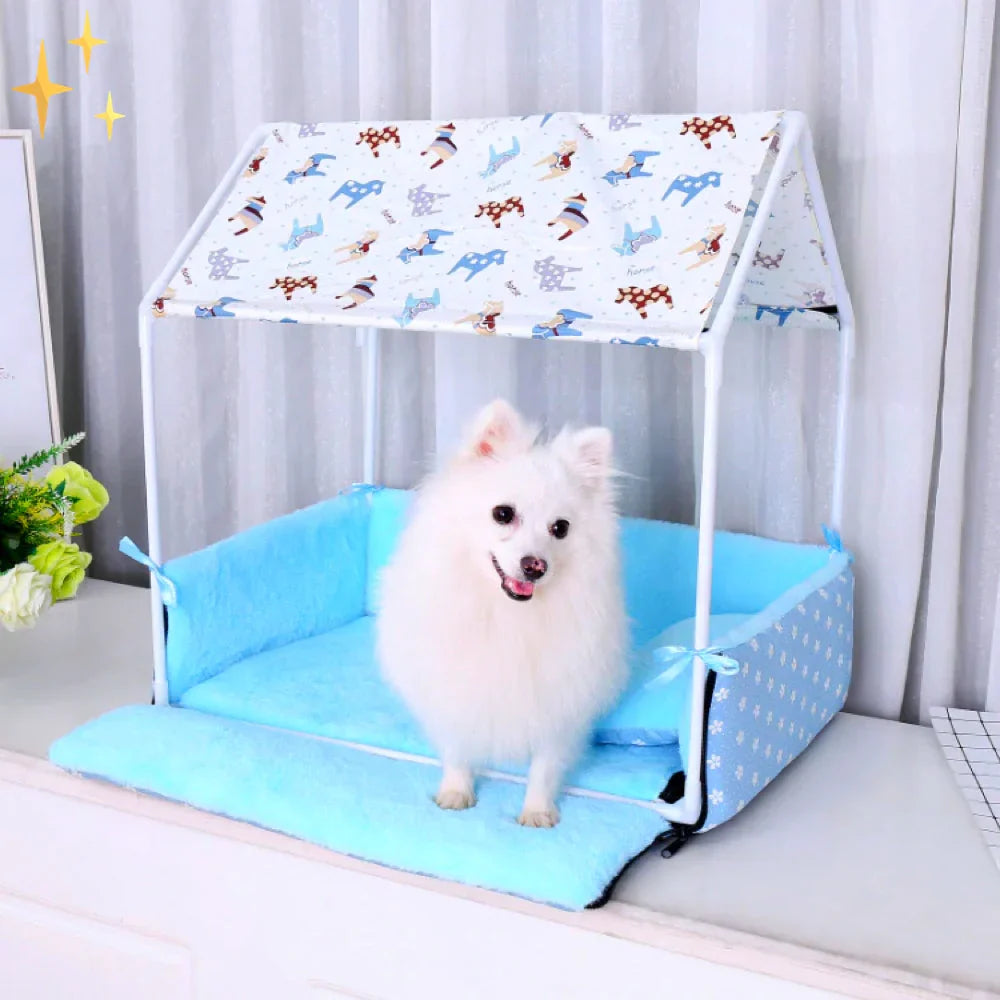 Dog bed with a printed canopy roof and light blue fleece mat, a small white spitz sitting inside