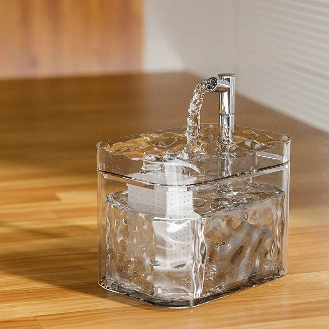 Clear pet water fountain with a wave-pattern tank and a tap-style spout pouring into the tray